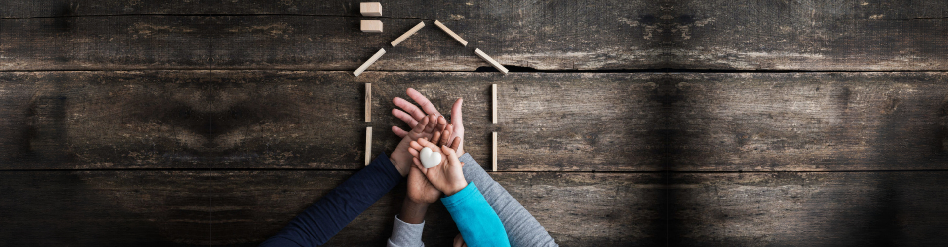 Family of four holding heart in house